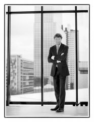 Bedrijfsportret in groothandelsgebouw in Rotterdam van directeur voor een grote glazen wand met gebouw Nationale Nederlanden op de achtergrond gefotografeerd op locatie door fotograaf. www.marijnissenfotografie.nl