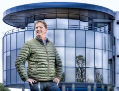 Bedrijfsportret fotografie van werknemer voor bedrijfspand rond met veel glas met blauwe gloed gefotografeerd op locatie door fotograaf. www.marijnissenfotografie.nl