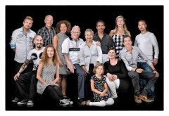Familieportret groepsfoto van 13 personen vader en moeder in het midden en de gezinnen daar omheen zittend en staand in een zwarte omgeving gefotografeerd in fotostudio Rotterdam. www.marijnissenfotografie.nl