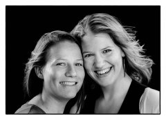 2 zussen close gefotografeerd met hun gezichten tegen elkaar gedrukt kijken in de camera en lachen gefotografeerd in de fotostudio Marijnissen Fotografie Rotterdam.