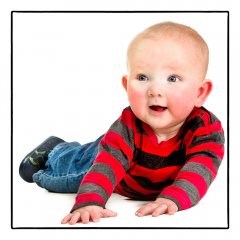 Babyfotografie van een baby die zichzelf opdrukt met zijn handjes voor hem op de vloer en net langs de camera kijkend gefotografeerd door fotograaf in de fotostudio. www.marijnissenfotografie.nl