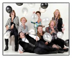 Verjaardagfeest fotoshoot met 7 dames allemaal kleding waar zwart en wit inzit op de voorgrond ligt de jarige en haar vriendinnen zitten eromheen en gooien ballonen de lucht in  gefotografeerd door fotograaf in de fotostudio Rotterdam  www.marijnissenfotografie.nl