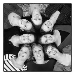 Vrijgezellendag feest close-up van vrouwen met hun rug op de vloer omhoog kijkend in de camera met de hoofden tegen elkaar in een rondje zodat het net een grote bloem lijkt gefotografeerd door fotograaf in de fotostudio Rotterdam  www.marijnissenfotografie.nl